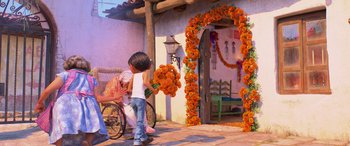 Movie still from “Coco” (2017), directed by Adrian Molina – A child holding a wreath of orange flowers; Wide shot, Over the shoulder angle