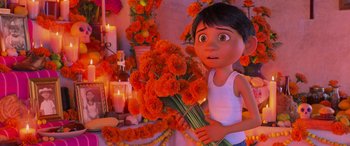 Movie still from “Coco” (2017), directed by Adrian Molina – A woman holding a bouquet of flowers in front of candles; Medium shot, Low angle