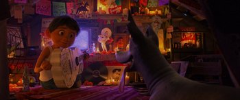 Movie still from “Coco” (2017), directed by Adrian Molina – A cat sitting on a table next to a person playing a guitar; Wide shot, Over the shoulder angle