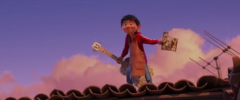 Movie still from “Coco” (2017), directed by Adrian Molina – An animated character holding a book and a guitar in front of a cloudy sky; Wide shot, Low angle