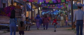 Movie still from “Coco” (2017), directed by Adrian Molina – A group of people walking down a street at night; Wide shot, Over the shoulder angle