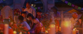 Movie still from “Coco” (2017), directed by Adrian Molina – A group of people gathered around a grave with candles; Wide shot, Over the shoulder angle