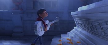 Movie still from “Coco” (2017), directed by Adrian Molina – A young boy holding a guitar in front of a staircase; Wide shot, Low angle
