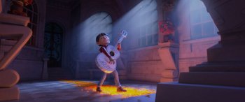 Movie still from “Coco” (2017), directed by Adrian Molina – A boy is holding a guitar in a room with lights; Wide shot, Low angle