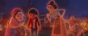Movie still from “Coco” (2017), directed by Adrian Molina – A boy and a woman are standing next to each other in a graveyard; Medium shot, Over the shoulder angle