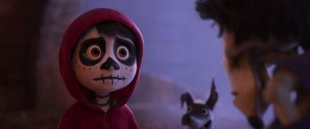 Movie still from “Coco” (2017), directed by Adrian Molina – A doll wearing a red hooded jacket and a dog wearing a red hooded jacket; Close Up shot, Over the shoulder angle