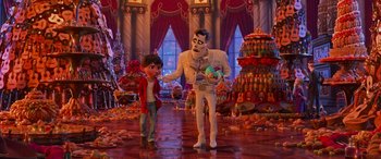 Movie still from “Coco” (2017), directed by Adrian Molina – A man and a boy are standing next to each other in a room filled with food; Wide shot, Over the shoulder angle