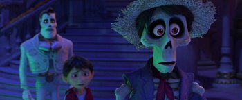 Movie still from “Coco” (2017), directed by Adrian Molina – A man and a boy are standing next to each other in front of a staircase; Medium shot, Over the shoulder angle