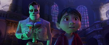 Movie still from “Coco” (2017), directed by Adrian Molina – A man and a boy are standing next to each other in front of stained glass windows; Medium shot, Low angle