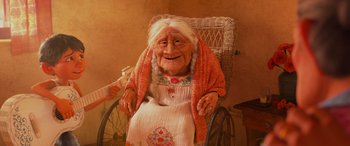 Movie still from “Coco” (2017), directed by Adrian Molina – An old woman sitting in a chair with a towel around her neck; Medium shot, Low angle