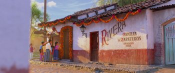 Movie still from “Coco” (2017), directed by Adrian Molina – A woman standing in front of a building decorated with flowers; Extreme Wide shot, Over the shoulder angle