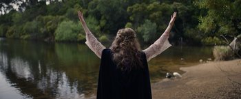 Movie still from “Color Out of Space” (2019), directed by Richard Stanley – A woman with her arms outstretched in front of a body of water; Medium shot, Over the shoulder angle