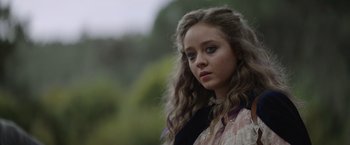 Movie still from “Color Out of Space” (2019), directed by Richard Stanley – A young woman with long hair is standing in a park; Close Up shot, Over the shoulder angle