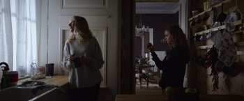 Movie still from “Color Out of Space” (2019), directed by Richard Stanley – Two women are standing in a room and one is holding an apple in her hand; Medium shot, Over the shoulder angle
