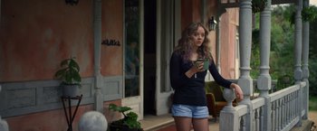 Movie still from “Color Out of Space” (2019), directed by Richard Stanley – A woman standing on a porch looking at her cell phone; Medium shot, Over the shoulder angle