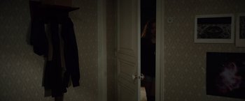 Movie still from “Color Out of Space” (2019), directed by Richard Stanley – A woman standing in a room with a door open; Medium shot, Over the shoulder angle