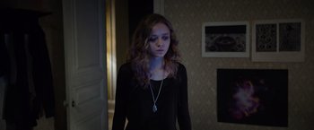 Movie still from “Color Out of Space” (2019), directed by Richard Stanley – A woman standing in front of a door wearing a necklace; Medium shot, Over the shoulder angle
