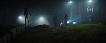 Movie still from “Color Out of Space” (2019), directed by Richard Stanley – A couple of people standing on top of a grass covered field; Wide shot, Low angle