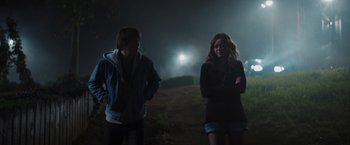 Movie still from “Color Out of Space” (2019), directed by Richard Stanley – A couple of people standing on top of a grass covered field; Medium shot, Over the shoulder angle