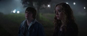 Movie still from “Color Out of Space” (2019), directed by Richard Stanley – A couple of people standing next to each other in the dark; Medium shot, Over the shoulder angle
