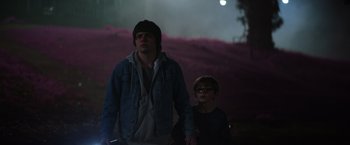 Movie still from “Color Out of Space” (2019), directed by Richard Stanley – A man standing next to a boy in a dark room; Medium shot, Low angle