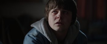 Movie still from “Color Out of Space” (2019), directed by Richard Stanley – A young man with a hooded jacket looking at the camera; Close Up shot, Low angle