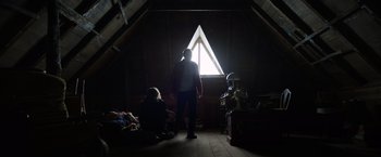 Movie still from “Color Out of Space” (2019), directed by Richard Stanley – A man standing in a room in front of an open window; Wide shot, Low angle