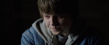 Movie still from “Color Out of Space” (2019), directed by Richard Stanley – A young man with a sad look on his face; Close Up shot, Over the shoulder angle
