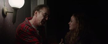 Movie still from “Color Out of Space” (2019), directed by Richard Stanley – A man and a woman are talking in a dark room; Medium shot, Over the shoulder angle