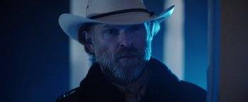 Movie still from “Color Out of Space” (2019), directed by Richard Stanley – A man with a white hat and beard; Close Up shot, Over the shoulder angle