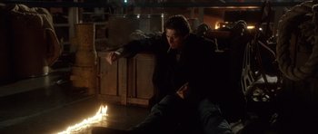 Movie still from “The Usual Suspects” (1995), directed by Bryan Singer – A man sitting on a couch in front of a fire; Medium shot, High angle
