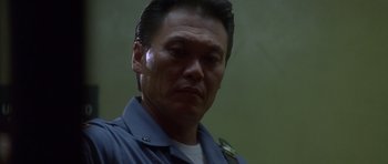 Movie still from “The Usual Suspects” (1995), directed by Bryan Singer – A person wearing a police uniform; Close Up shot, Low angle