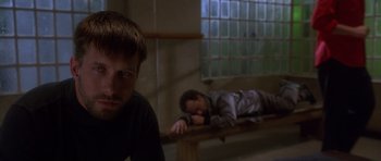 Movie still from “The Usual Suspects” (1995), directed by Bryan Singer – Two men are lying on a bench in a room; Medium shot, High angle