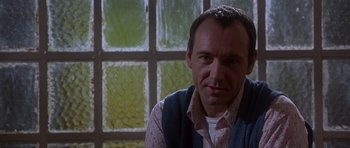 Movie still from “The Usual Suspects” (1995), directed by Bryan Singer – A person sitting in front of a window; Close Up shot, Low angle
