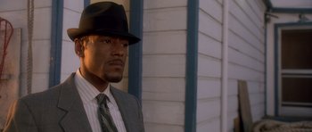 Movie still from “The Usual Suspects” (1995), directed by Bryan Singer – A man wearing a suit and tie and a hat; Close Up shot, Low angle