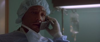 Movie still from “The Usual Suspects” (1995), directed by Bryan Singer – A man in a surgical gown talking on a cell phone; Close Up shot, Low angle