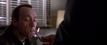 Movie still from “The Usual Suspects” (1995), directed by Bryan Singer – A person lighting a candle in a man's mouth; Close Up shot, Low angle