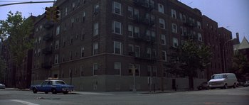 Movie still from “The Usual Suspects” (1995), directed by Bryan Singer – A tall brick building on a street corner; Extreme Wide shot, High angle