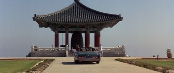Movie still from “The Usual Suspects” (1995), directed by Bryan Singer – A couple of people standing next to a car in front of a building; Extreme Wide shot, High angle