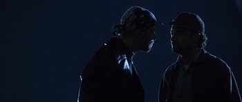 Movie still from “The Usual Suspects” (1995), directed by Bryan Singer – A man wearing a hat is looking at another man; Close Up shot, Over the shoulder angle