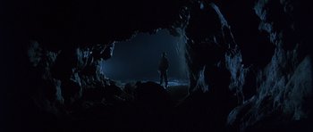 Movie still from “The Usual Suspects” (1995), directed by Bryan Singer – A man standing inside of a cave at night; Wide shot, Low angle
