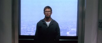 Movie still from “The Usual Suspects” (1995), directed by Bryan Singer – A man standing in front of a large window; Medium shot, Low angle