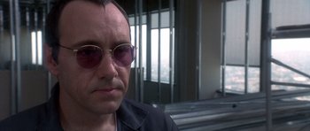 Movie still from “The Usual Suspects” (1995), directed by Bryan Singer – A person wearing sunglasses; Close Up shot, Over the shoulder angle