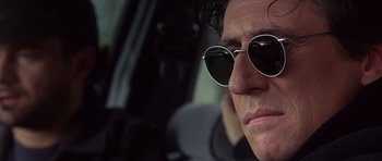 Movie still from “The Usual Suspects” (1995), directed by Bryan Singer – A person wearing sunglasses in a car; Close Up shot, Low angle