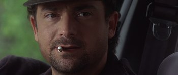 Movie still from “The Usual Suspects” (1995), directed by Bryan Singer – A person wearing a hat smoking a cigarette; Close Up shot, Low angle