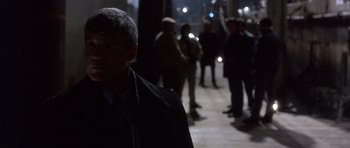 Movie still from “The Usual Suspects” (1995), directed by Bryan Singer – A group of people standing in a dark room; Medium shot, Over the shoulder angle