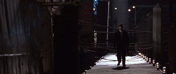 Movie still from “The Usual Suspects” (1995), directed by Bryan Singer – A man standing in a dark alley next to a building; Wide shot, Low angle