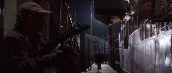 Movie still from “The Usual Suspects” (1995), directed by Bryan Singer – A man walking down a street at night with a gun; Wide shot, Low angle