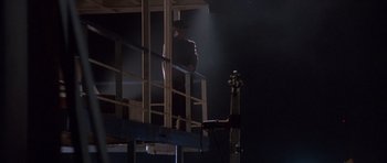 Movie still from “The Usual Suspects” (1995), directed by Bryan Singer – A man standing on top of a building in the dark; Wide shot, Low angle