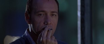 Movie still from “The Usual Suspects” (1995), directed by Bryan Singer – A person smoking a cigarette; Close Up shot, Low angle